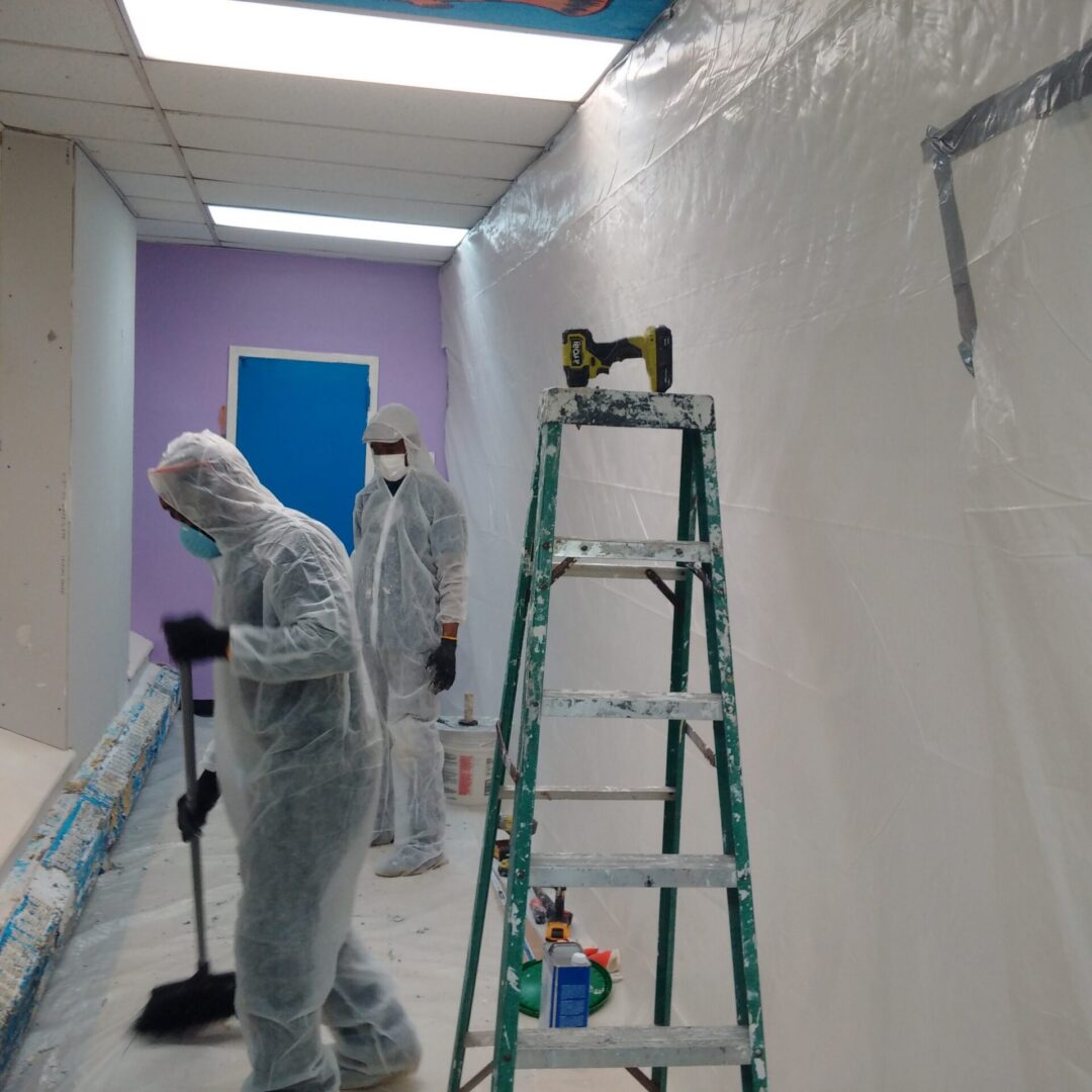 Workers in protective suits renovating interior room