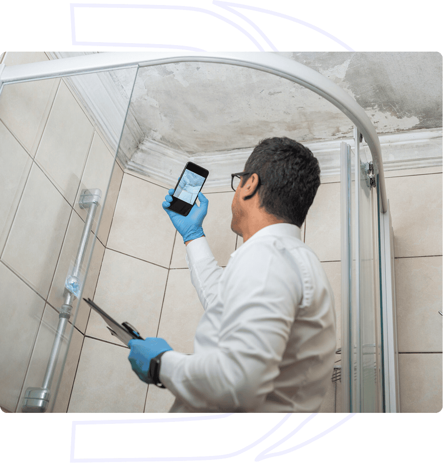 Man inspecting bathroom ceiling with smartphone.